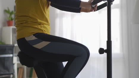 workout-with-stationary-bike-in-home-woman-is-spinning-pedals-keeping-fit-and-losing-weight-slender-female-body-details-shot